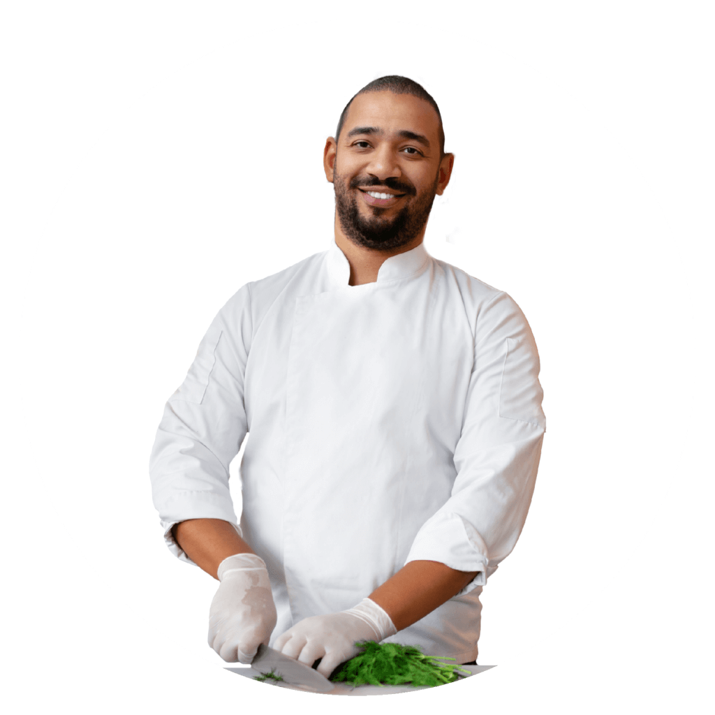 A chef wearing white cuts greens with a knife