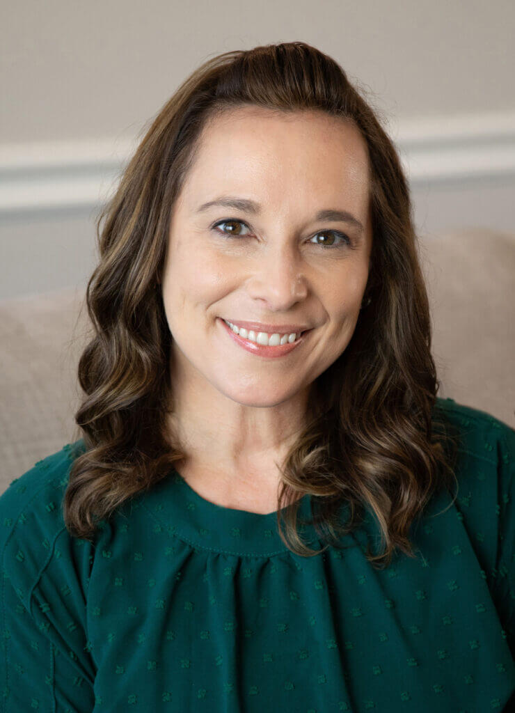 a woman in a green shirt smiles for the camera