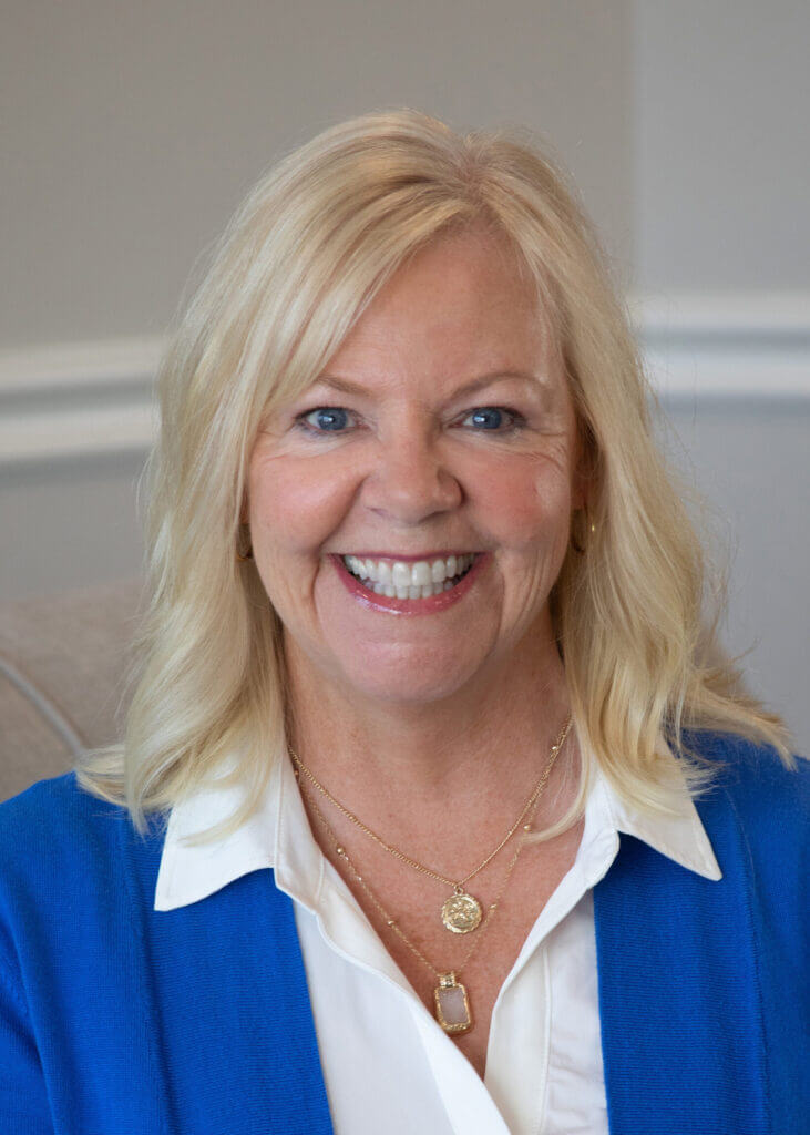 a woman wearing a blue jacket and a white shirt smiles for the camera