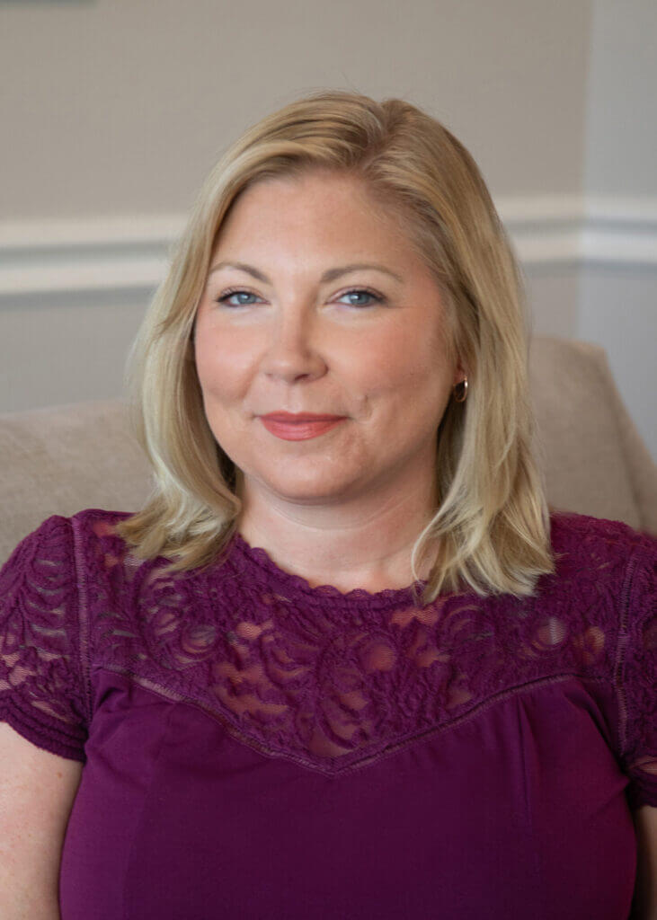 a woman in a purple lace top smiles for the camera