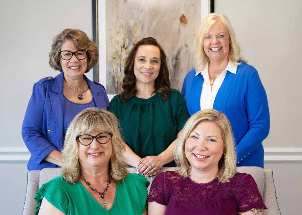 a group of women posing for a picture with two wearing glasses