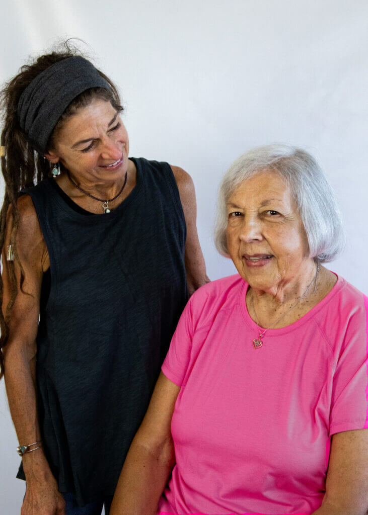 a woman in a black tank top stands next to an older woman in a pink shirt