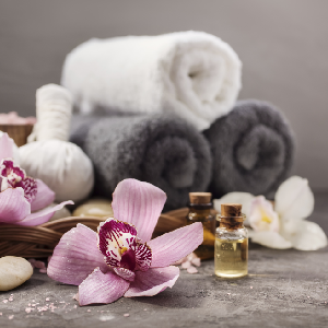 Rolled spa blankets sit next to essential oils and hibiscus flowers