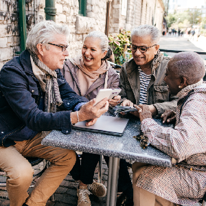 Two elderly couples look at phones while sitting around a table