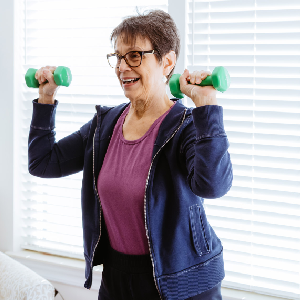 An elderly female lifts light weights